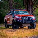 An Old Man Emu Toyota Hilux with easy installation of ARB Old Man Emu Front Coil Springs 2887, resulting in an increased ride height, parked on a dirt road.