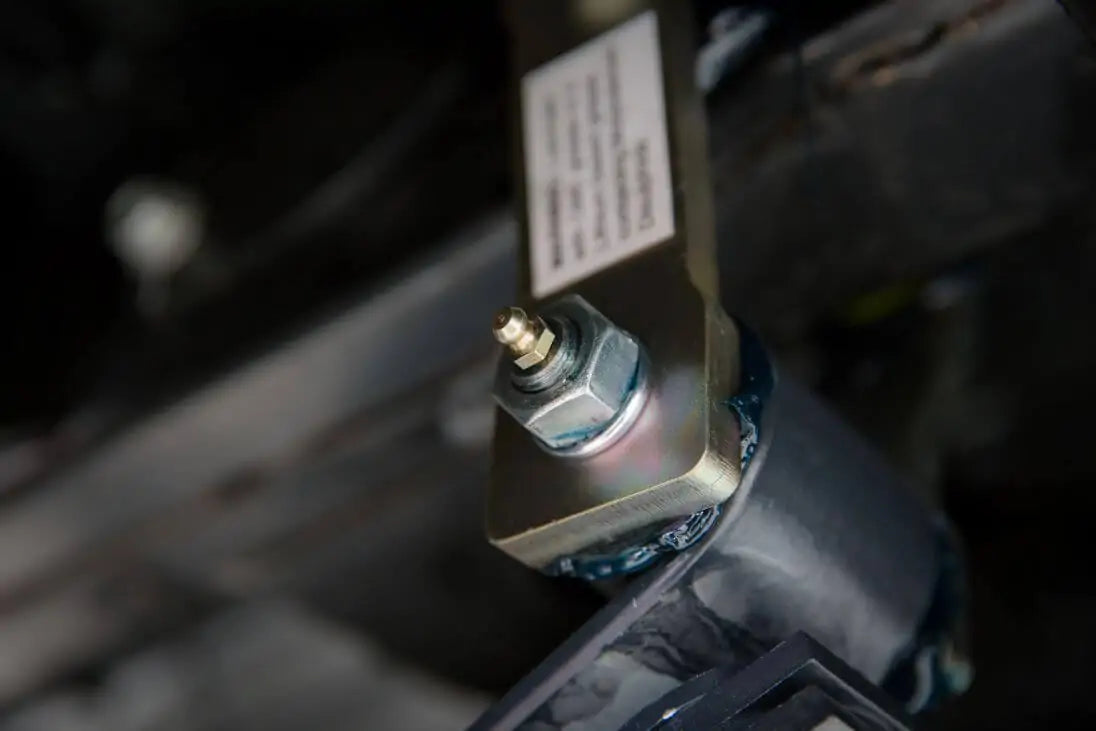 A close up of a car with a wire attached to its OME Rear Leaf Spring Shackle OMEGS12 for Toyota Tacoma V6 (1998-2004) Old Man Emu shackles for improved ride quality from ARB.