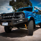 An Old Man Emu blue Ford Bronco with an ARB Trim Packer Kit FK111 (21-ON) suspension system parked in a parking lot.