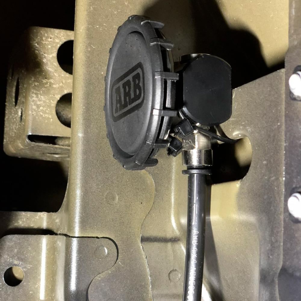 A black and white picture of ARB Differential Breather Kit 170112, made by ARB, with a hose attached to its axle.