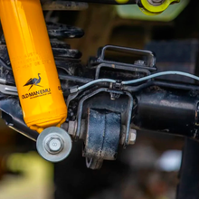 Load image into Gallery viewer, A close up of a yellow ARB Old Man Emu Rear Nitrocharger Sport 60155 suspension on a vehicle with heavy gauge reserve tube.