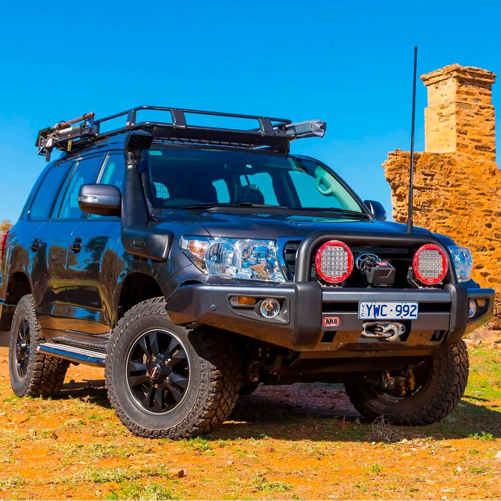 A black Toyota Land Cruiser with secure storage and an ARB Roof Rack Fitting Kit for Land Rover Discovery HT3 year 1998 ARB 3700080 parked on a dirt road.