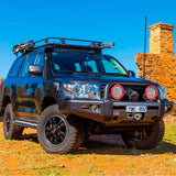 A black Toyota Land Cruiser with secure storage and an ARB Roof Rack Fitting Kit for Land Rover Discovery HT3 year 1998 ARB 3700080 parked on a dirt road.
