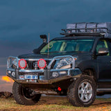 A black Old Man Emu Toyota Land Cruiser parked on a dirt road with a lifted suspension.