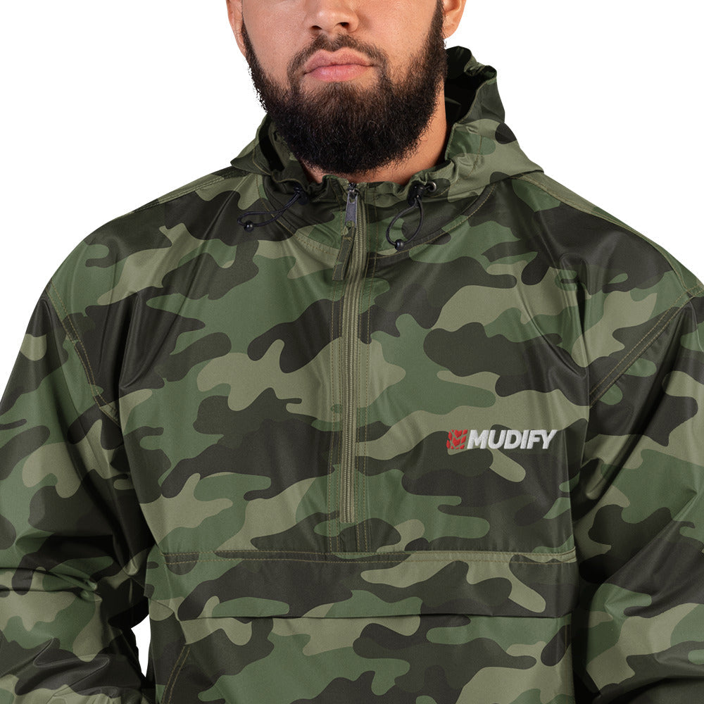 A man wearing the Mudify Embroidered Mudify Packable Jacket, wind and rain resistant.