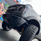 The front end of a black truck with graffiti on it featuring a unique ride height and custom suspension, equipped with the ARB Trim Packer Kit FK111 for Ford Bronco (21-ON) by Old Man Emu.