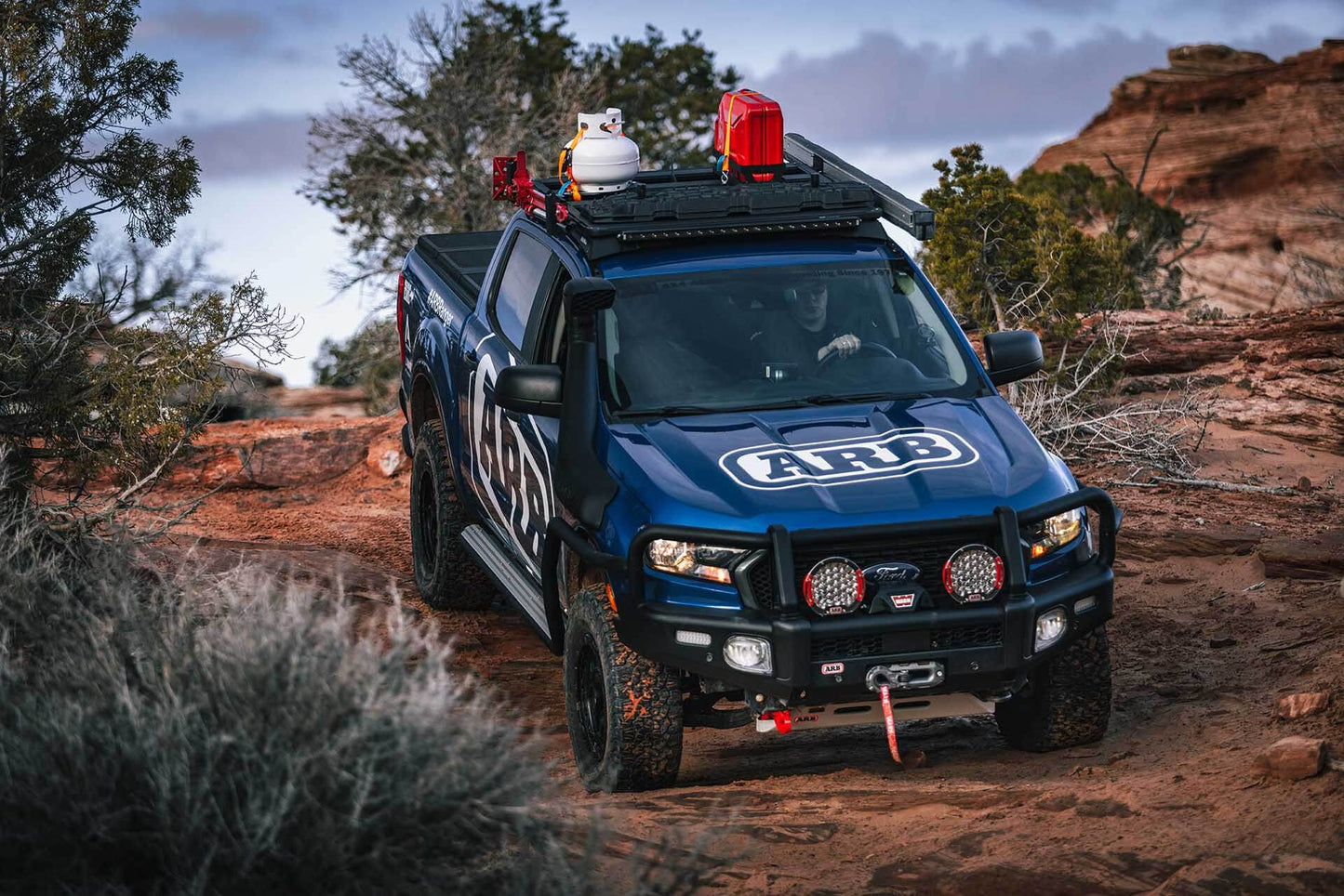 A steel blue ARB Rated LHS Recovery Point for Toyota Hilux 2814020 is driving down a rocky trail.