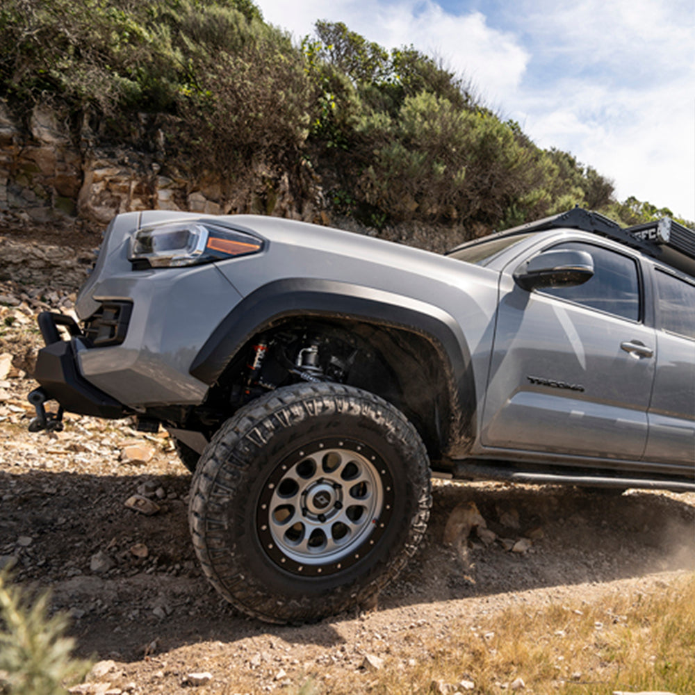 The 2019 Toyota Tacoma, equipped with the Fox Racing 2.0 Performance Series 2.0 Front Coil-Over IFP Shock 985-02-002 for Toyota Tacoma 4WD and RWD/ 4Runner / FJ Cruiser / Land Cruiser Prado 120 (Pair), is effortlessly conquering a rocky trail.