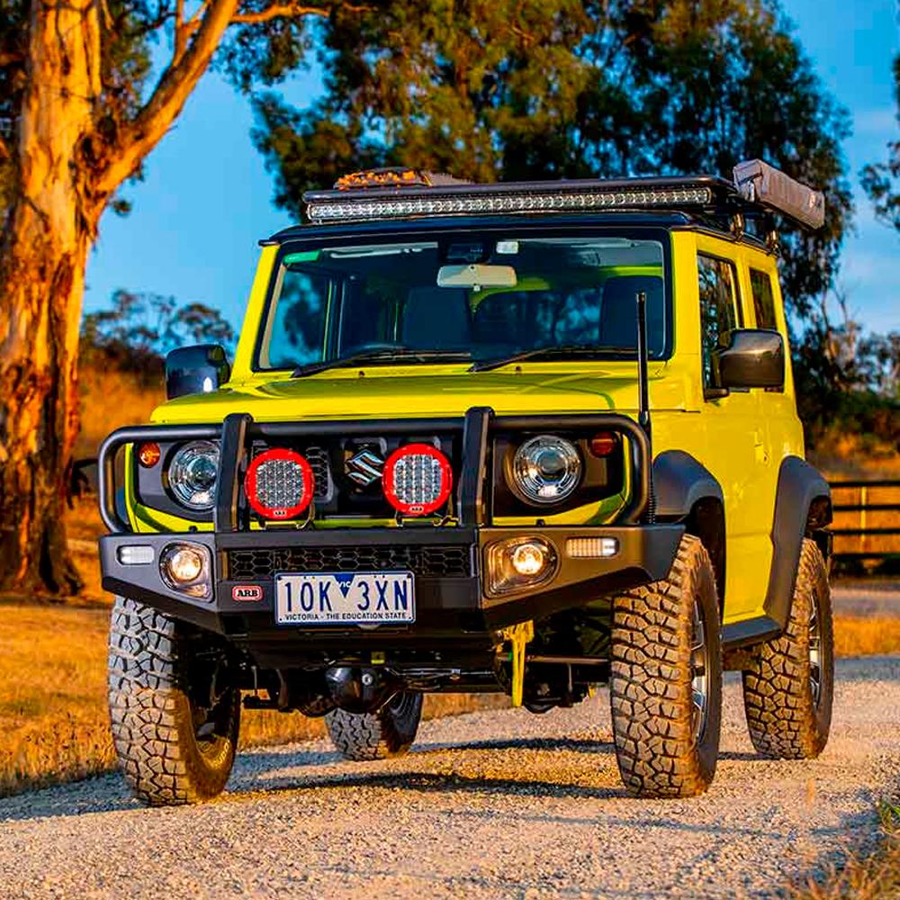 A yellow Suzuki Jimmy driving down a dirt road, boasting easy installation and offering oxidation protection for the ARB Old Man Emu Rear Coil Springs 2898 for Toyota 4Runner, FJ Cruiser, Prado 150 Series (LWB MODELS) 1.5 inch Estimated Lift by Old Man Emu.