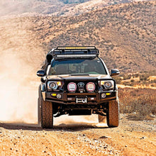 Load image into Gallery viewer, An Old Man Emu Toyota Tacoma is equipped with Old Man Emu nitrogen gas compression valving and a heavy gauge reserve tube as it confidently drives down a dirt road.
