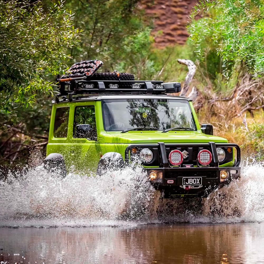 A green Nissan Old Man Emu FJ Cruiser driving through a river, offering easy installation and oxidation protection.