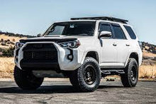 Load image into Gallery viewer, The white 2019 Toyota 4Runner, equipped with an ARB LED Fog Light Kit for Toyota 3500910 bumper, is parked on a dirt road.
