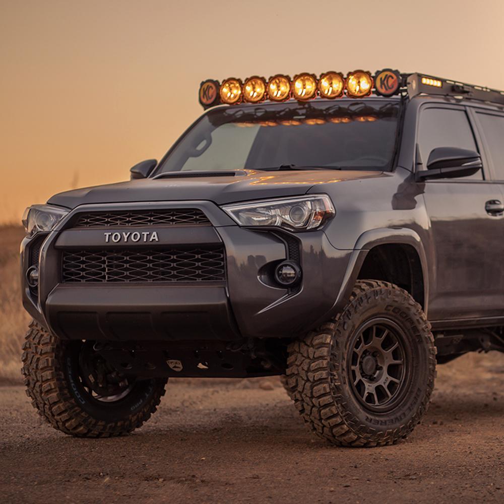 The 2019 Old Man Emu Toyota Prado 90 Series/Tacoma V6 & 4 Cylinder/4Runner/Toyota Surf, known for its easy installation and ride height, is parked on a dirt road.