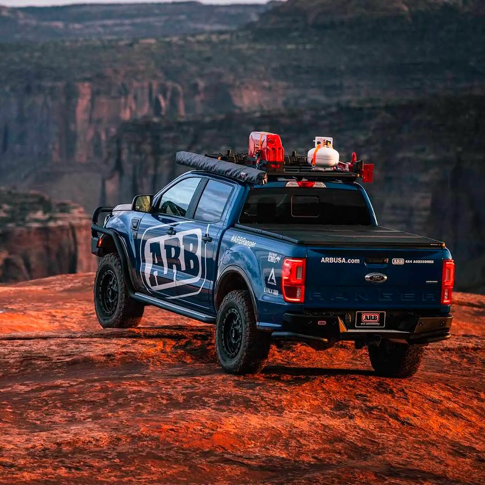 A blue Old Man Emu Ford Ranger with OME Shock Stone Guard Kit OME661 for Toyota Land Cruiser 150 Series, 4Runner, FJCruiser is parked on a rocky cliff.