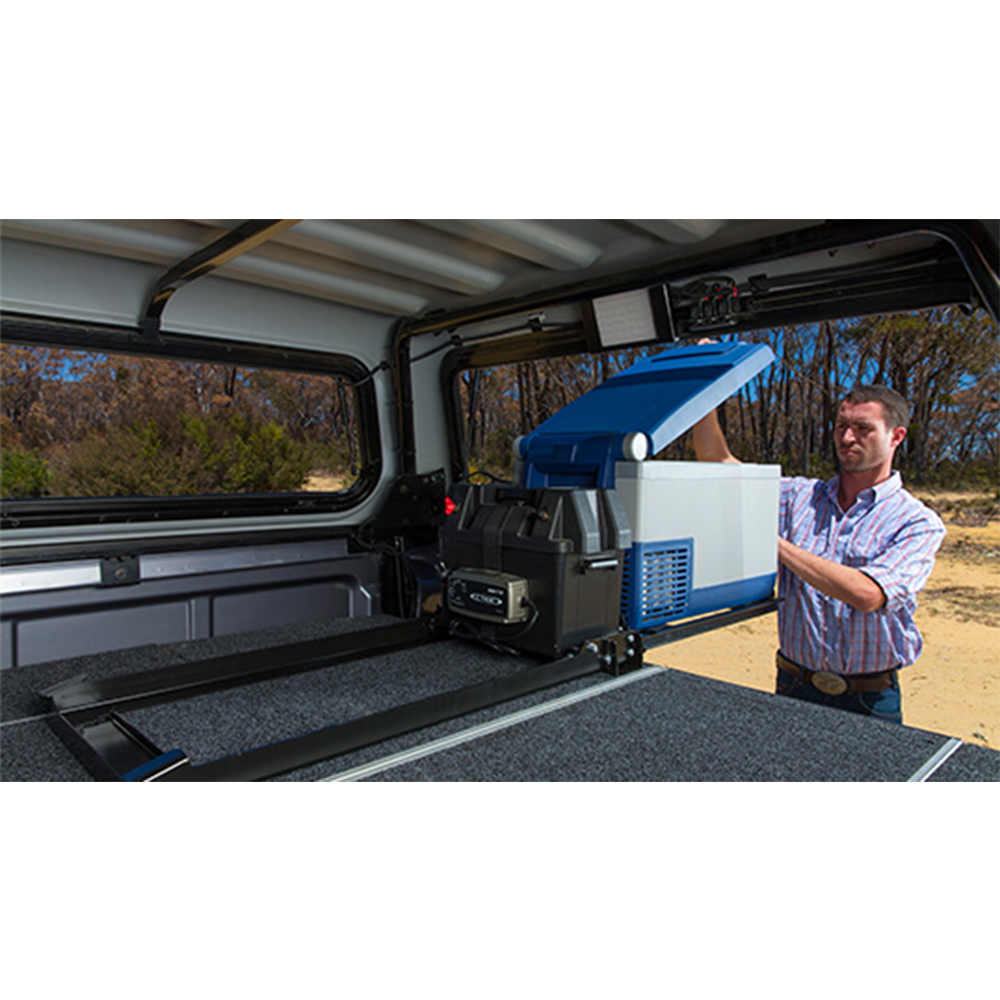 A man carefully installing the ARB Threaded Socket Surface Mount Outlet for ARB Fridge 10900028 in the back of a truck.