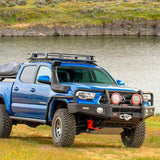 A blue ARB Toyota Tacoma parked next to a lake, suitable for cargo transportation.