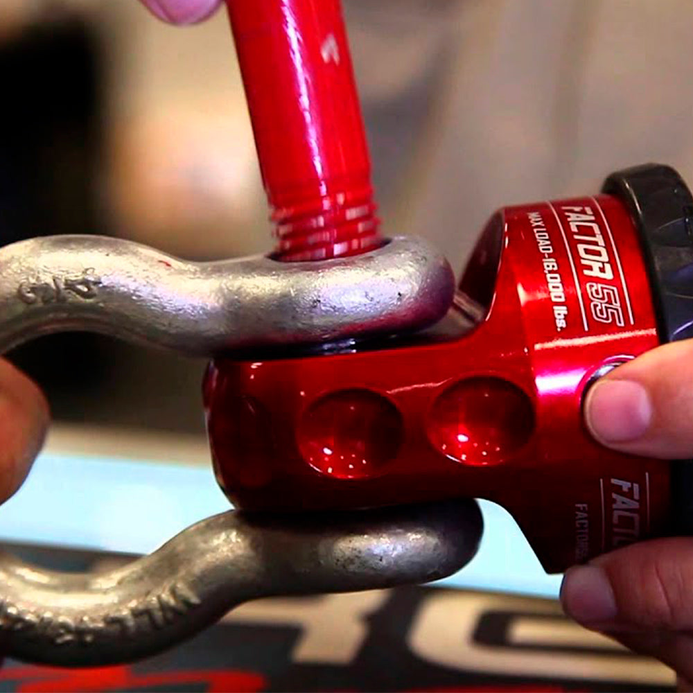 A person is holding a Factor 55 ProLink XXL Shackle Mount Assembly in Red 00210-01 made of 6000 series billet aluminum on a bike.