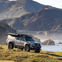Load image into Gallery viewer, A rust resistant Fox Racing Toyota Tacoma RWD equipped with the FOX 2.0 Performance Series 2.0 Front Coil-Over IFP Shock 985-02-002 for Toyota Tacoma 4WD and RWD/ 4Runner / FJ Cruiser / Land Cruiser Prado 120 (Pair) is parked on a hill near the ocean.
