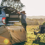 A man is efficiently setting up a durable ARB Zero 38 Quart Portable Fridge Freezer Single Zone 10802362 tent in the back of a SUV.