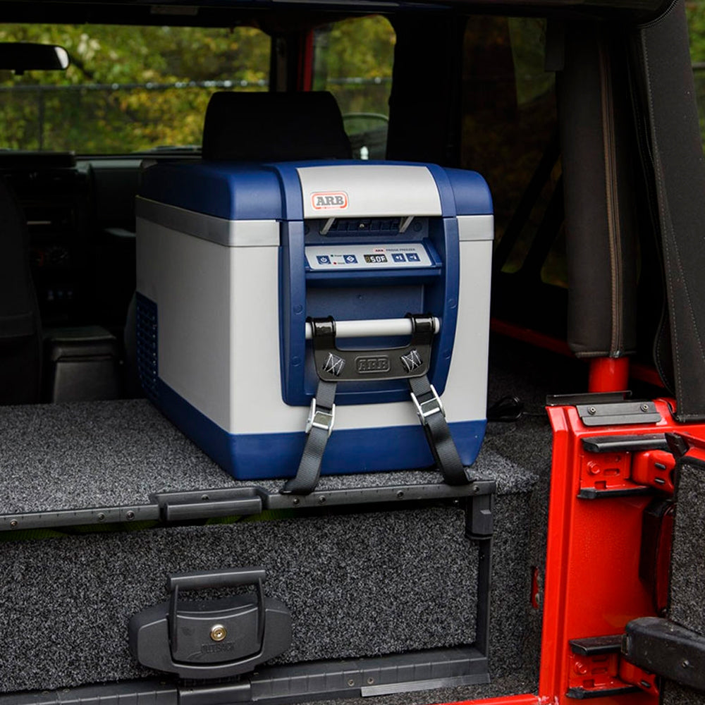 A ARB Fridge Freezer 82 Qt 10800782 is placed prominently in the back of a jeep, with its sleek design and durable construction making it a must-have product for any outdoor enthusiast. With strategic placement of keywords, this ARB