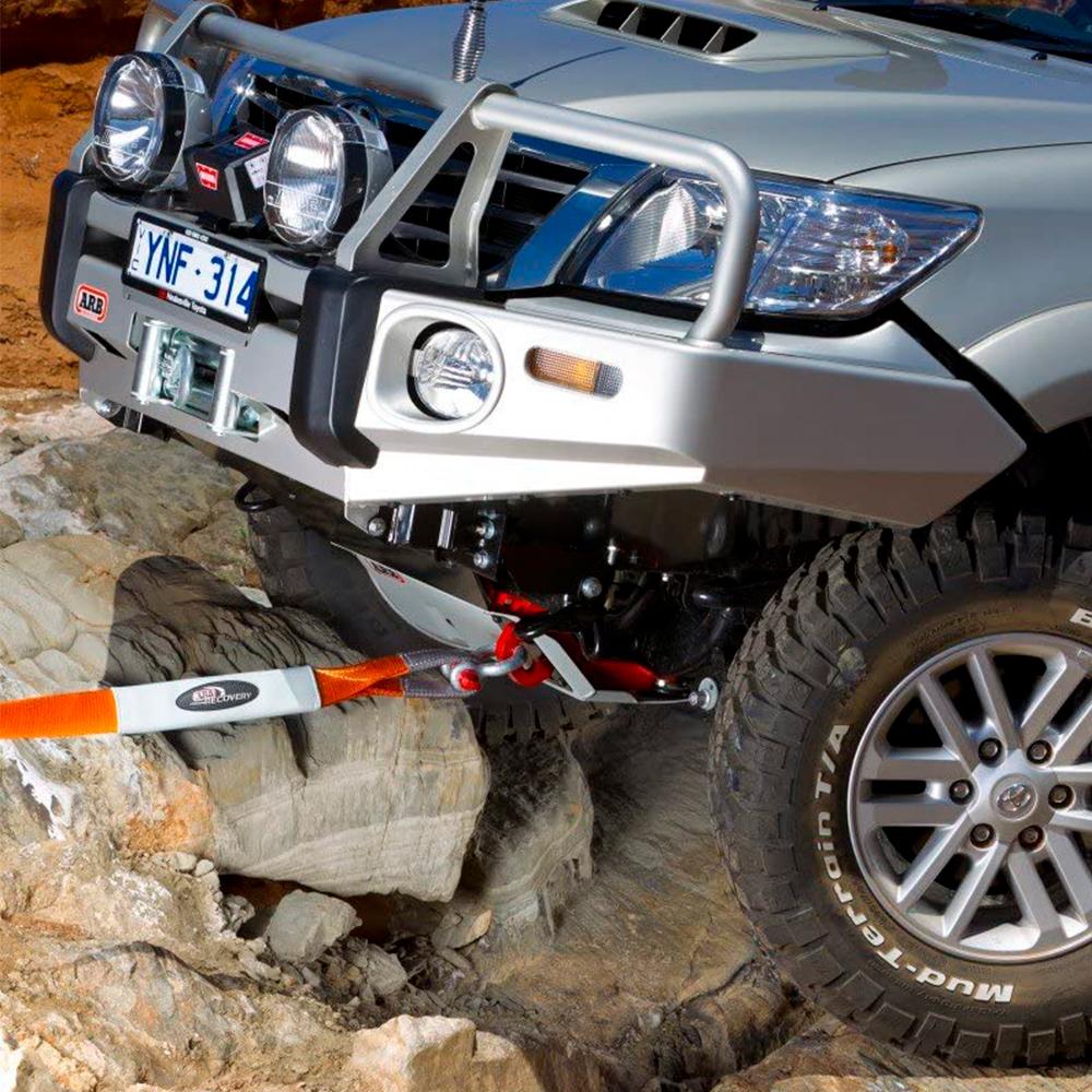 A Toyota Tacoma equipped with ARB vehicle recovery gear is securely parked on a rock using a snatch block strap from ARB715LB.