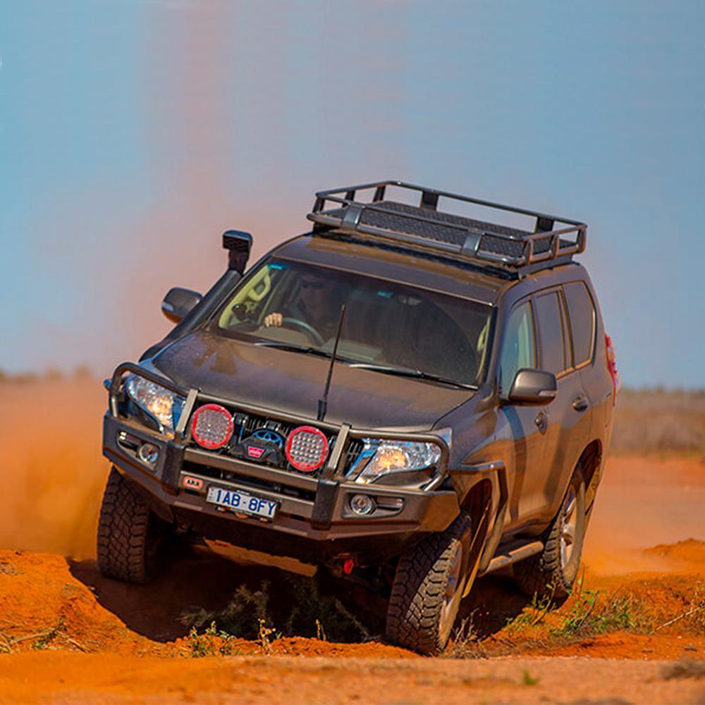 An ARB Roof Rack Fitting Kit for Land Rover Discovery HT3 year 1998 ARB 3700080 with high capacity is driving through the desert, equipped with secure storage.