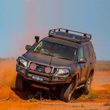 An ARB Roof Rack Fitting Kit for Land Rover Discovery HT3 year 1998 ARB 3700080 with high capacity is driving through the desert, equipped with secure storage.