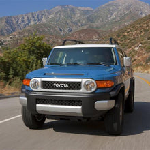 Load image into Gallery viewer, A blue Toyota FJ Cruiser with Old Man Emu BP-51 2.5 - 3 inch Lift Kit for FJ Cruiser (10-ON) shock absorbers is driving down a mountain road.