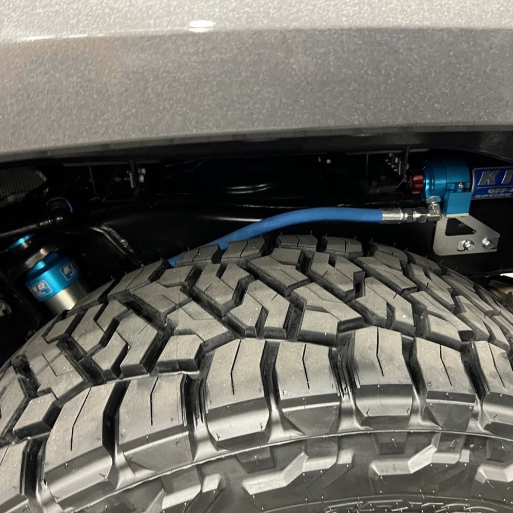 An off-road performance Jeep Wrangler with enhanced stability and King shocks, with a blue hose attached to it.