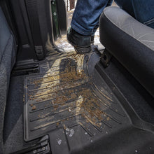 Load image into Gallery viewer, A person is standing in the back seat of a vehicle equipped with Weathertech Floorliner HP 2nd Row Floor Mats, suitable for extreme weather environments.